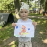 Маленький ребенок рисует яркими красками на природе